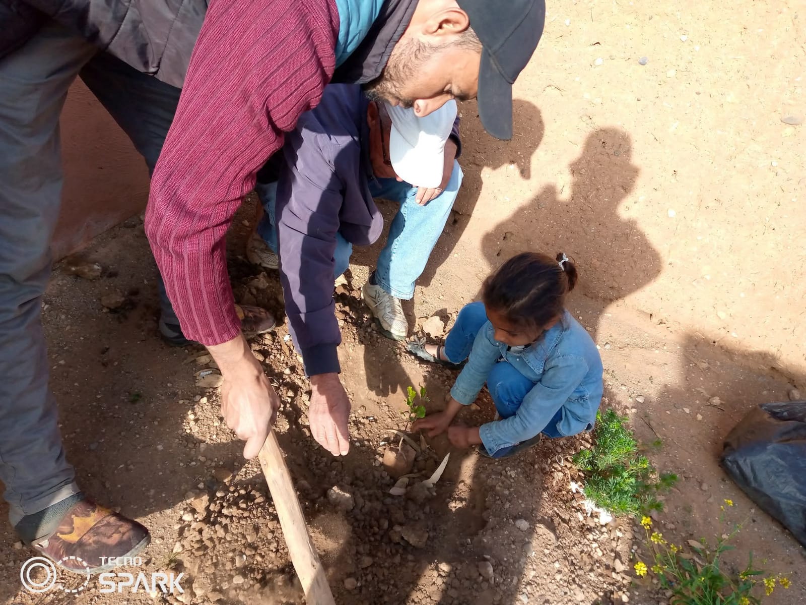 Adult mentoring a student planting a tree